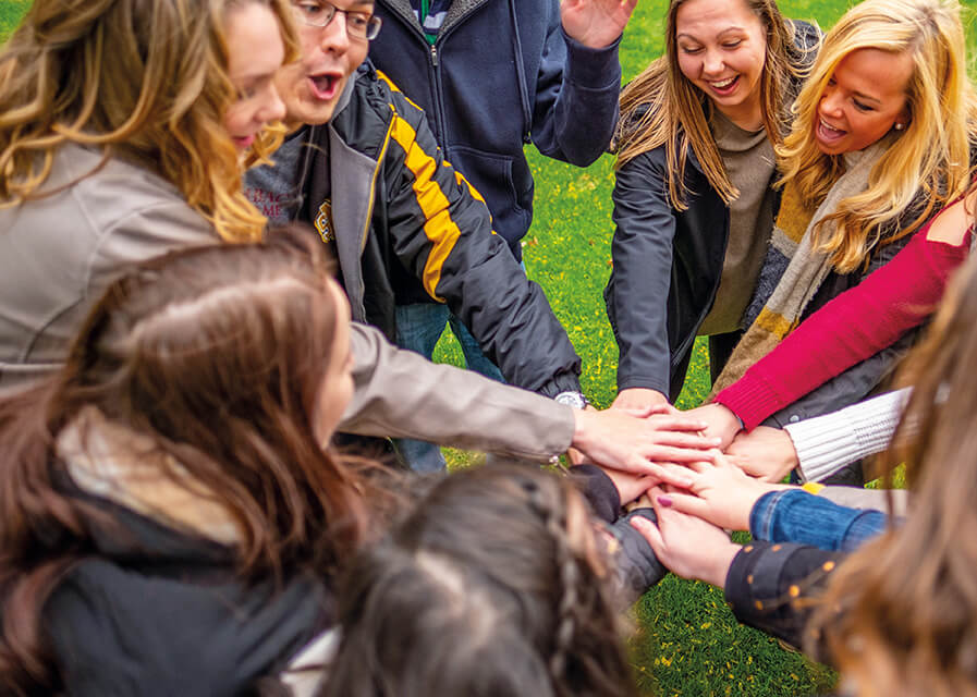 Students in a circle with their hands extended