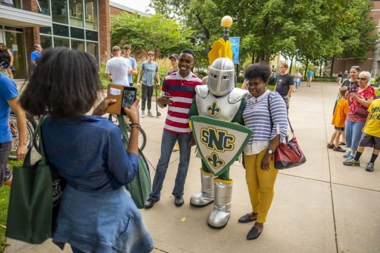 Two students posing for a photo with the school mascot